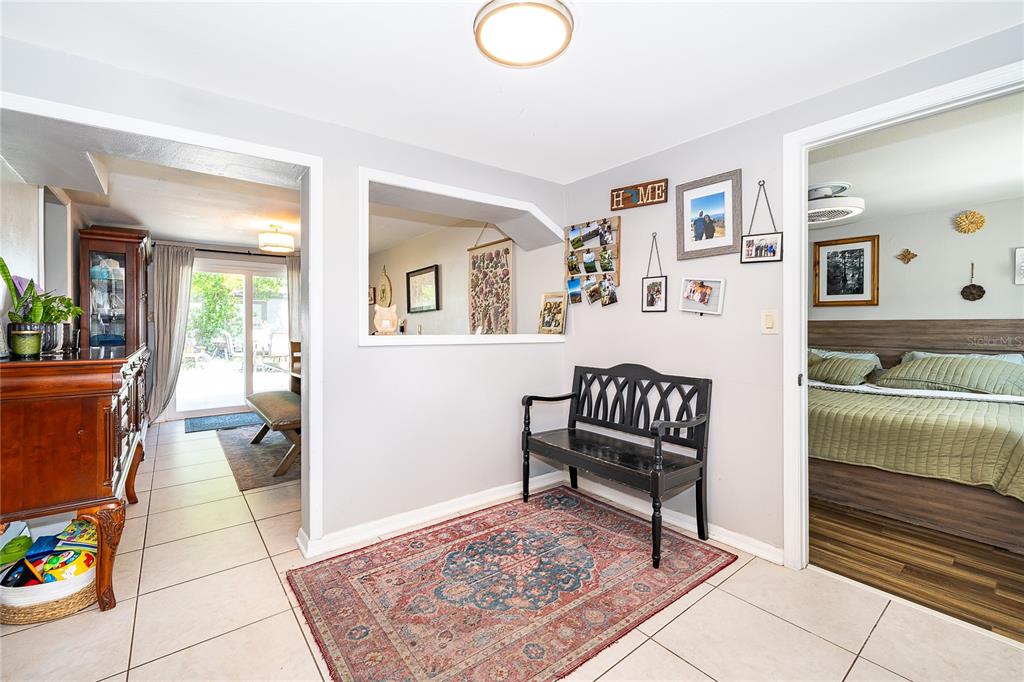 A tiled entryway features a black bench, a patterned rug, and a wall-mounted photo display — 1624 HOLLIS DRIVE, ORLANDO, FL