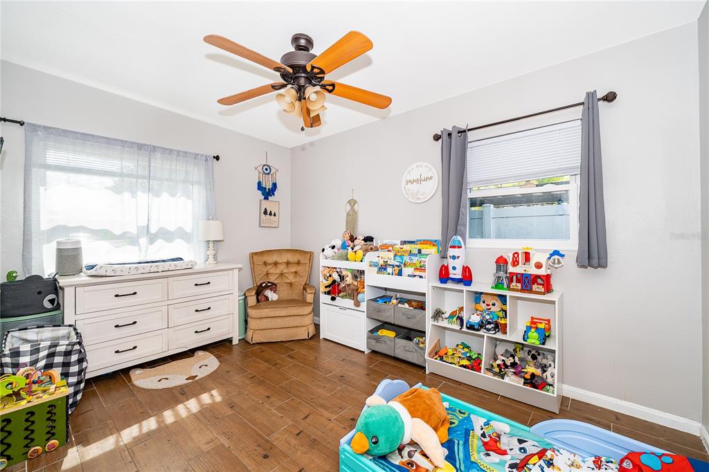 A child's bedroom features wood-look tile flooring, a ceiling fan, a dresser, and toy storage — 1624 HOLLIS DRIVE, ORLANDO, FL