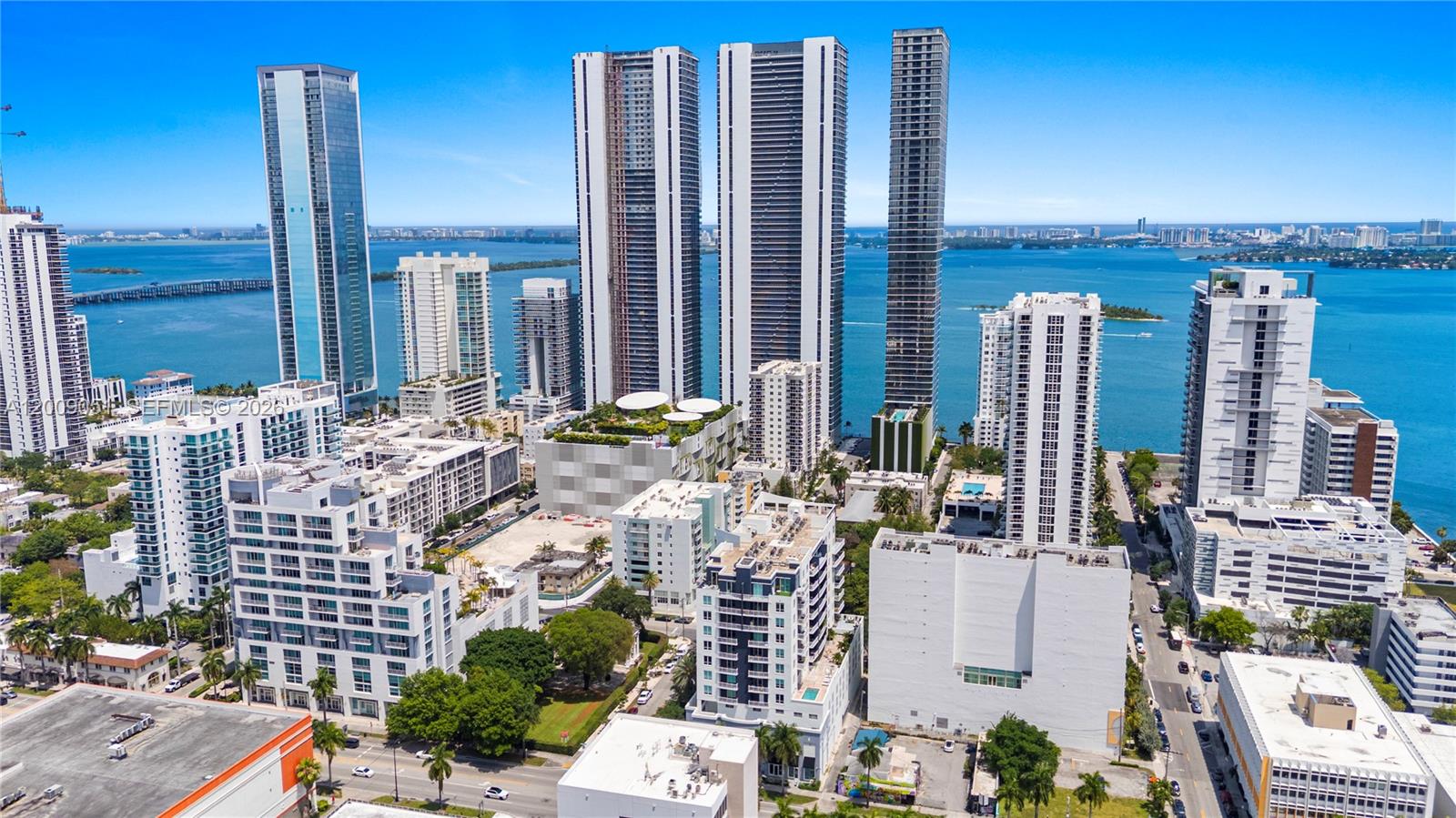 An aerial view shows high-rise apartment buildings and urban development along a waterfront — 2275 Biscayne Blvd # 802, Miami FL 33137, MIAMI, FL
