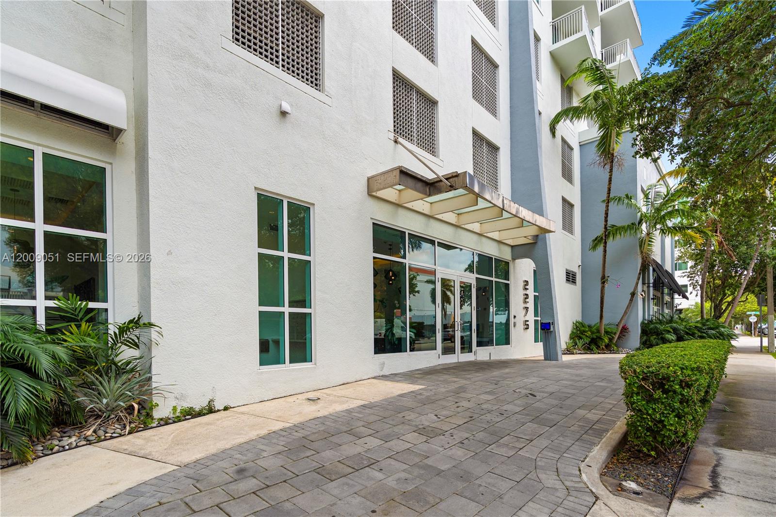 The exterior of a multi-story building features a glass entrance canopy and a paved driveway — 2275 Biscayne Blvd # 802, Miami FL 33137, MIAMI, FL