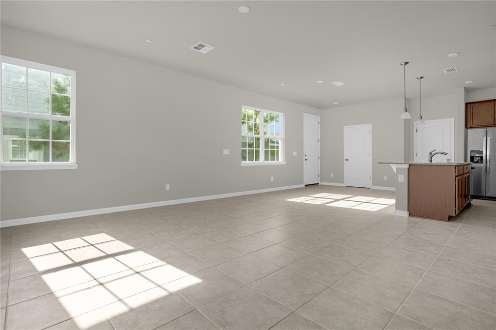 An open-concept living area features light-colored tile flooring, neutral walls, and a kitchen island — 1927 HOLDEN RIDGE LANE, CLERMONT, FL