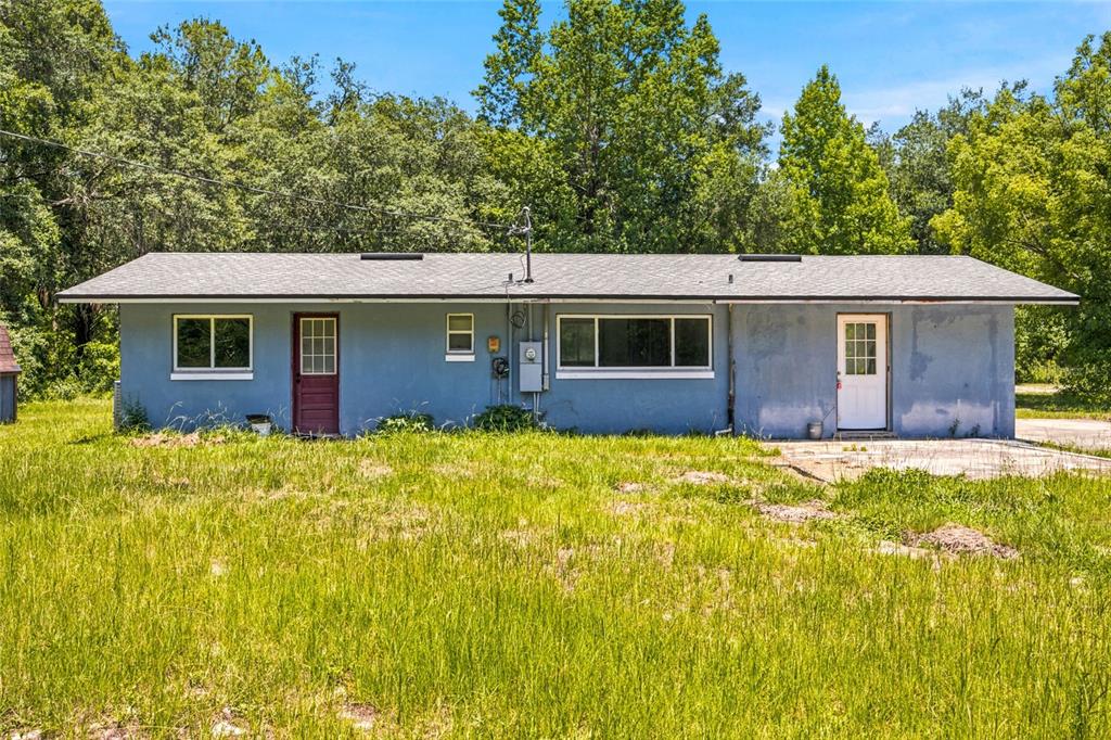 A single-story blue house with two doors and a large window sits in a field — 14600 NE 150TH AVENUE, FORT MC COY, FL