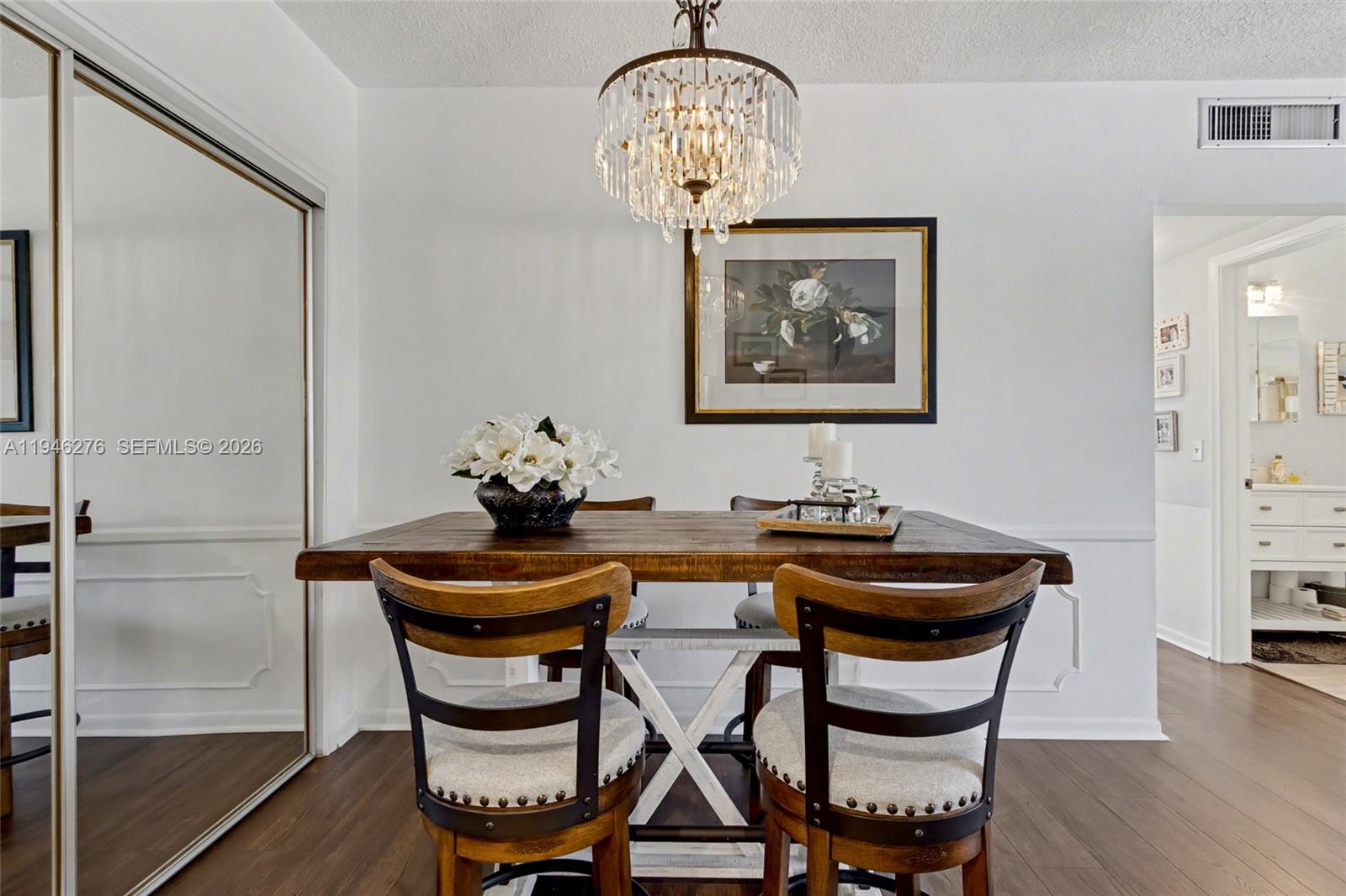 A dining room features a wooden table, four chairs, and a crystal chandelier — 412 S Cypress Rd # 222, Pompano Beach FL 33060, POMPANO BEACH, FL