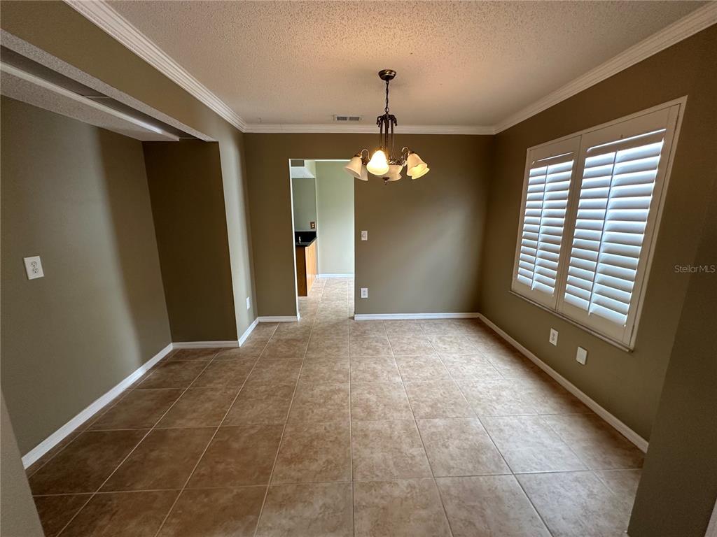 A dining room with tan tile flooring, a chandelier, and white plantation shutters — 3837 HOLSTON WAY, ORLANDO, FL