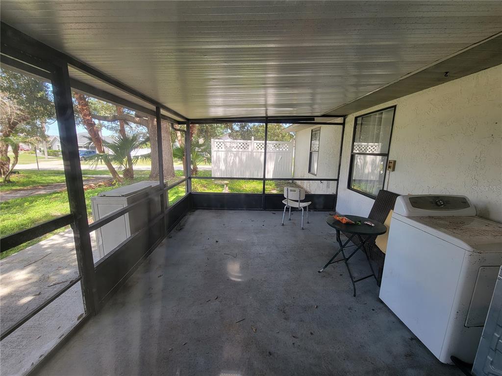 A screened-in porch with a concrete floor, a washing machine, and a small table — 2218 GRETNA DRIVE, DELTONA, FL