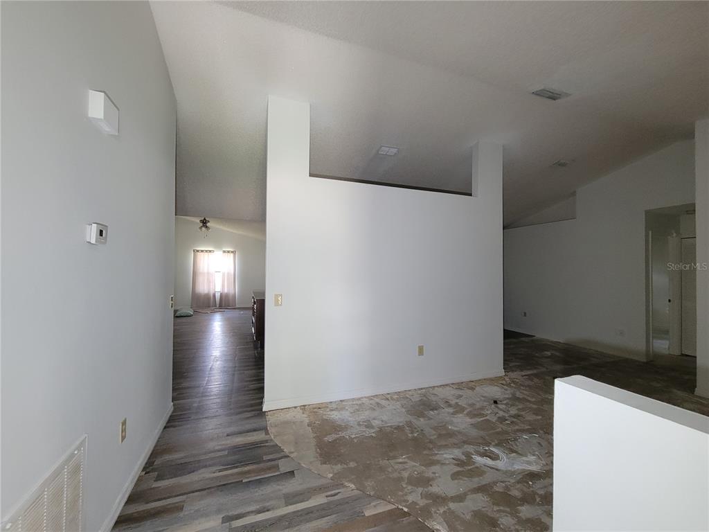 An interior view showing a room with unfinished concrete flooring and a partial wall divider — 2218 GRETNA DRIVE, DELTONA, FL