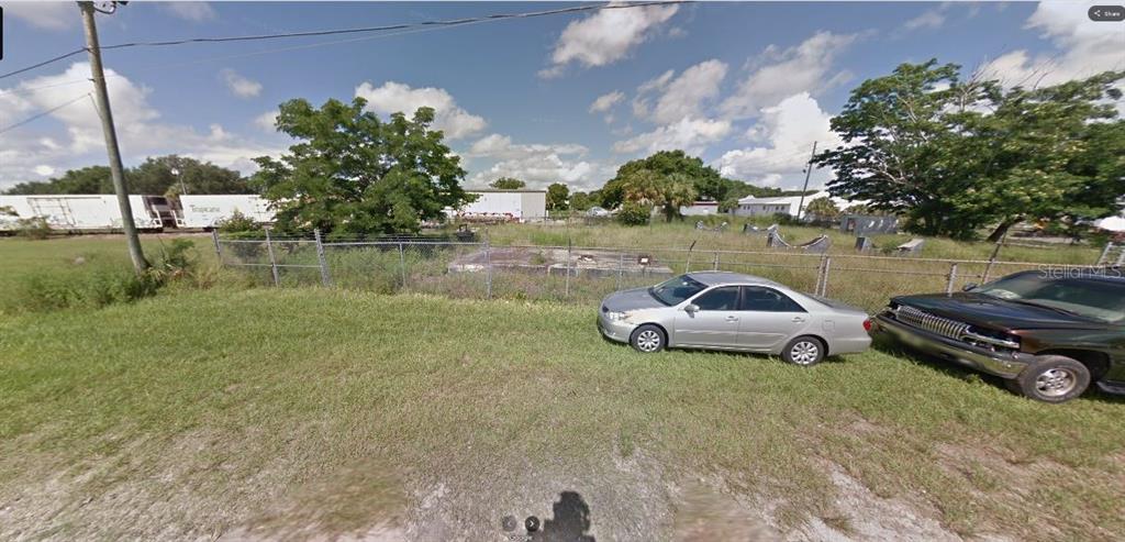A grassy lot with two parked cars and a chain-link fence in front of trees — 60 E STREET, LAKE WALES, FL