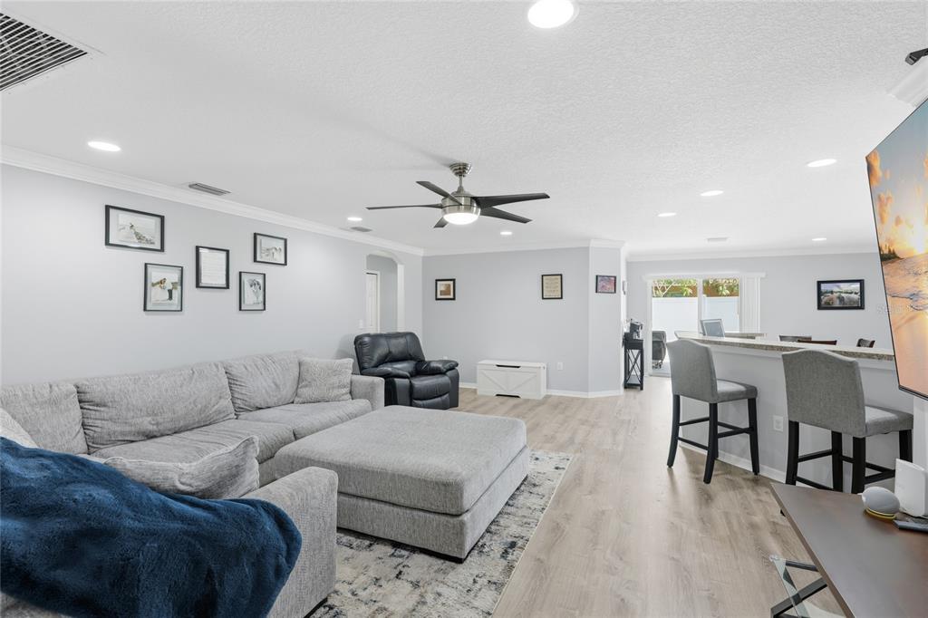 A living room features a gray sectional sofa, a ceiling fan, and a breakfast bar — 1202 HUMBLE HAVEN STREET, RUSKIN, FL
