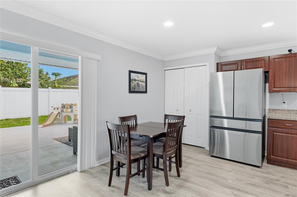 A dining area with a table, chairs, stainless steel refrigerator, and sliding glass patio doors — 1202 HUMBLE HAVEN STREET, RUSKIN, FL