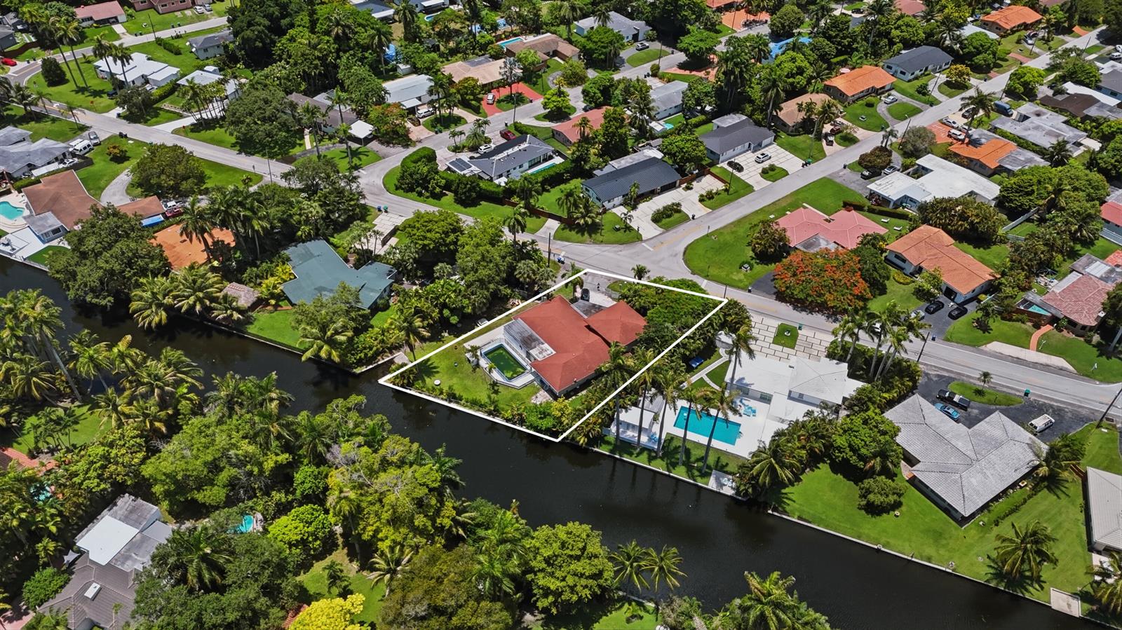 An aerial view shows a house with a red roof and pool beside a canal — 11401 W Biscayne Canal Road, Miami FL 33161, MIAMI, FL