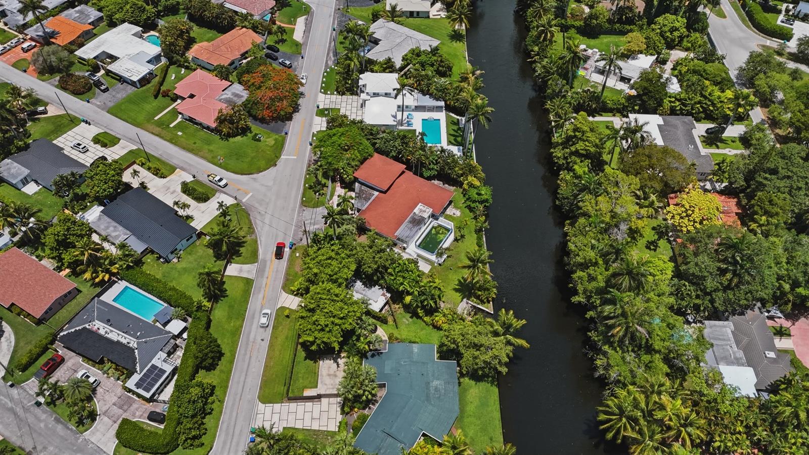 An aerial view shows residential homes with swimming pools along a canal in a neighborhood — 11401 W Biscayne Canal Road, Miami FL 33161, MIAMI, FL