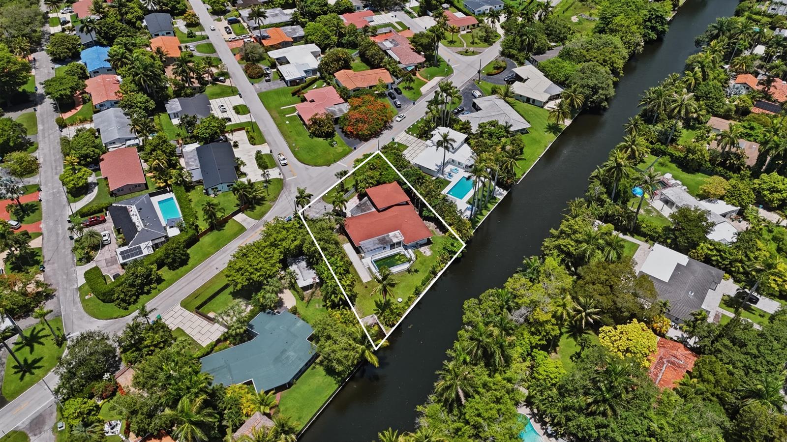 An aerial view shows a house with a red roof, pool, and canal-front backyard — 11401 W Biscayne Canal Road, Miami FL 33161, MIAMI, FL