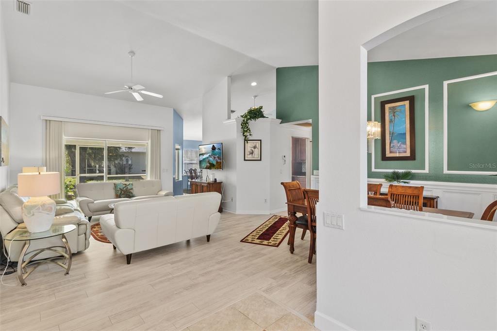 A living room and dining area feature white walls, light wood flooring, and green accents — 4812 KENVIL DRIVE, NORTH PORT, FL