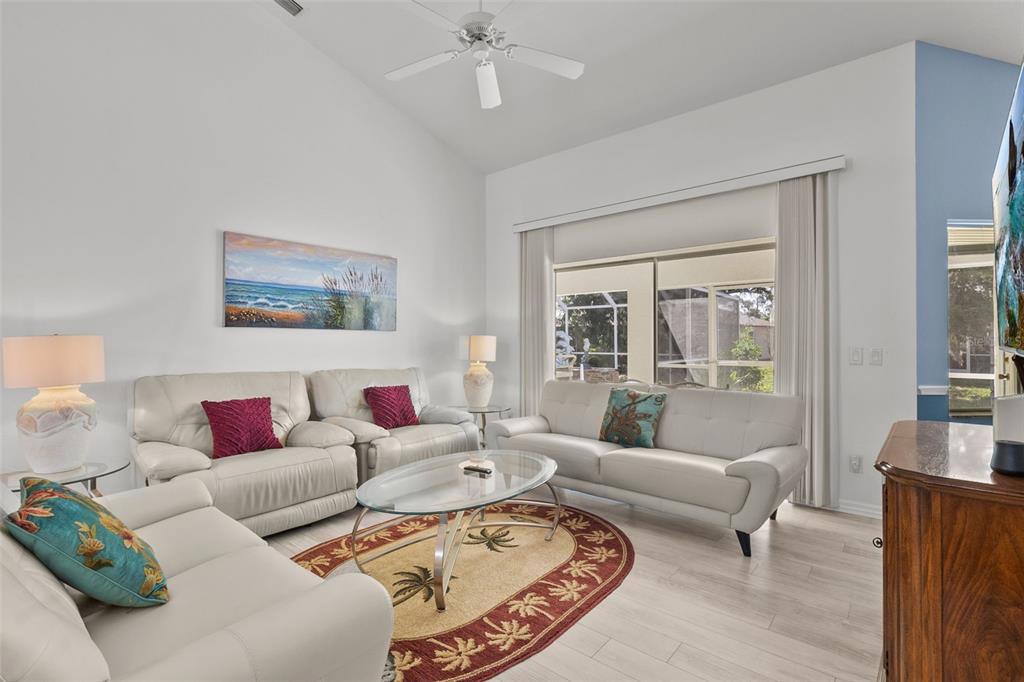 A living room features white leather sofas, a glass coffee table, and a vaulted ceiling — 4812 KENVIL DRIVE, NORTH PORT, FL