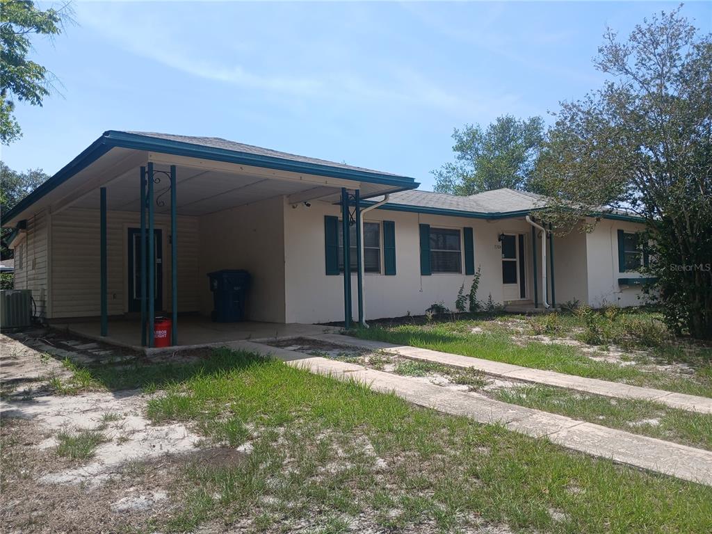 A single-story house with a carport, beige siding, and dark green shutters — 7304 ACORN CIRCLE, SPRING HILL, FL
