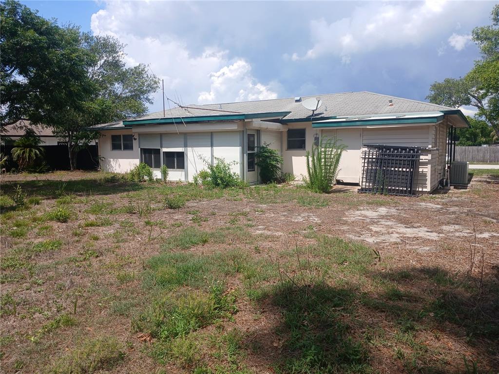 The exterior of a single-story house features a screened-in porch and a large, grassy yard — 7304 ACORN CIRCLE, SPRING HILL, FL