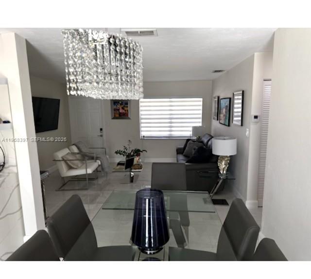 A dining area with a glass table leads into a living room with a crystal chandelier — 10752 SW 141st Ln, Miami FL 33176, MIAMI, FL