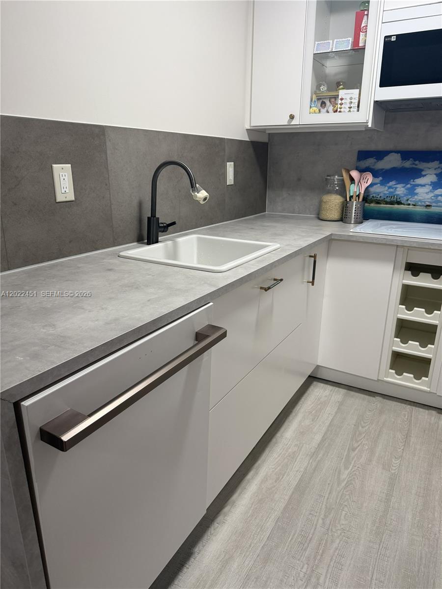 A modern kitchen features white cabinets, a gray countertop, and a black faucet — HOLLYWOOD, FL