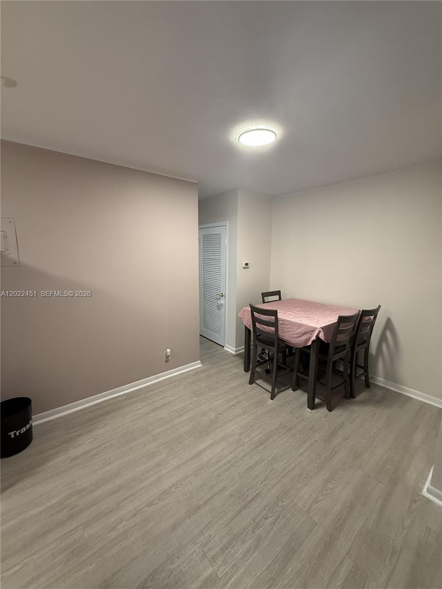 A dining area features light wood-look flooring, a table with four chairs, and a closet — HOLLYWOOD, FL