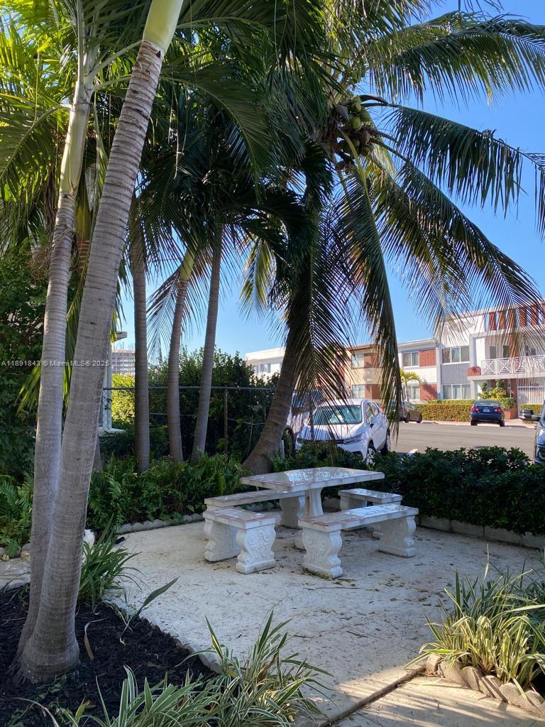 A stone picnic table and benches sit on a patio beneath palm trees outdoors — 7435 Byron Ave, Miami Beach FL 33141, MIAMI BEACH, FL