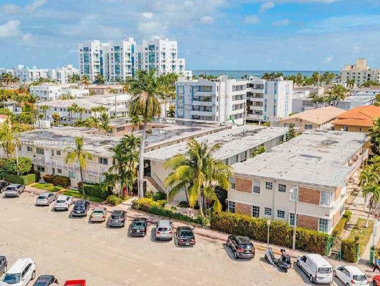 An aerial view of a multi-story apartment complex with a parking lot and palm trees — 7435 Byron Ave, Miami Beach FL 33141, MIAMI BEACH, FL