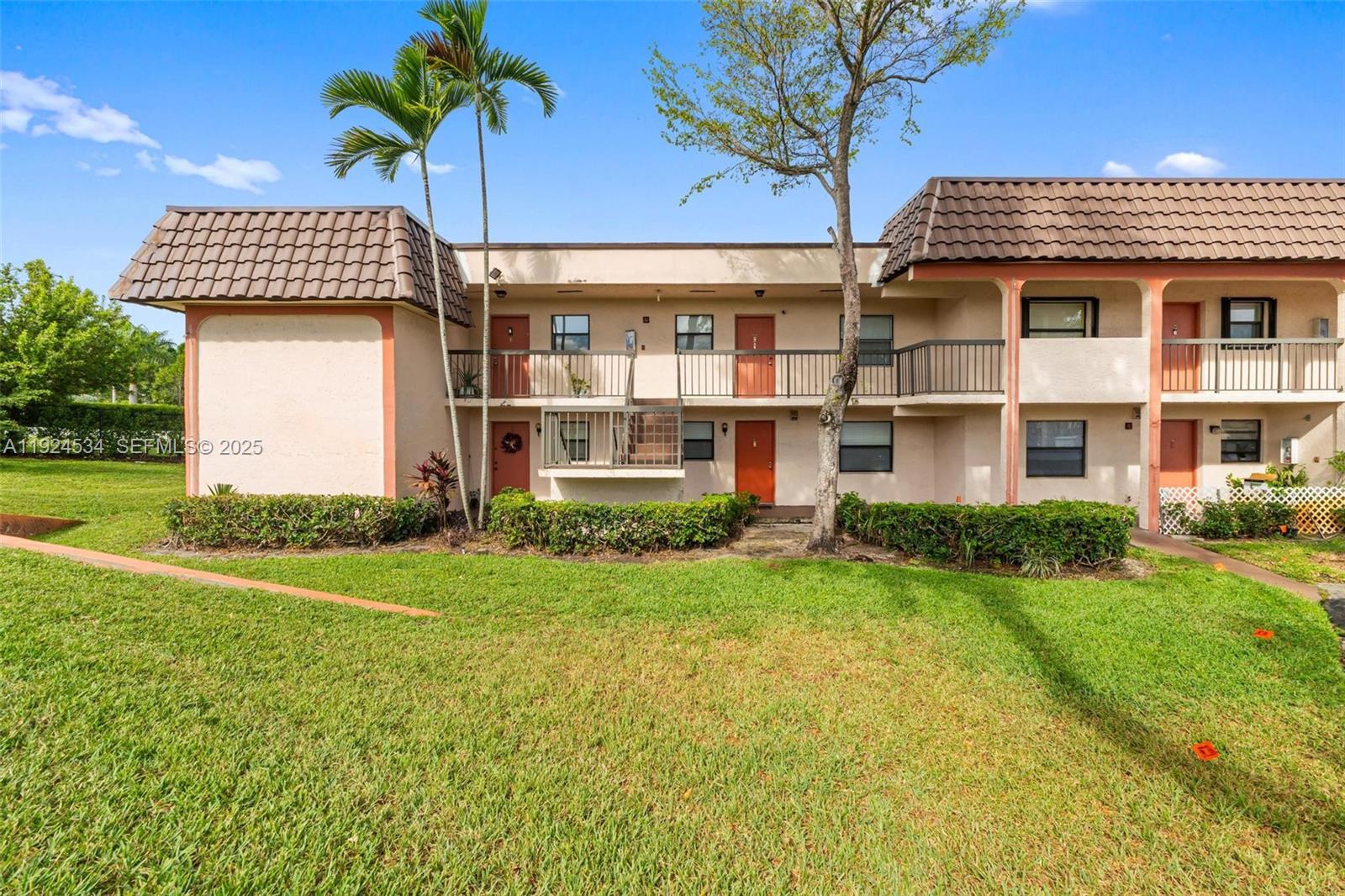 A two-story apartment building features a tan stucco exterior, brown tiled roof, and balconies — 821 NE 207th Ln # 1, Miami FL 33179, MIAMI, FL
