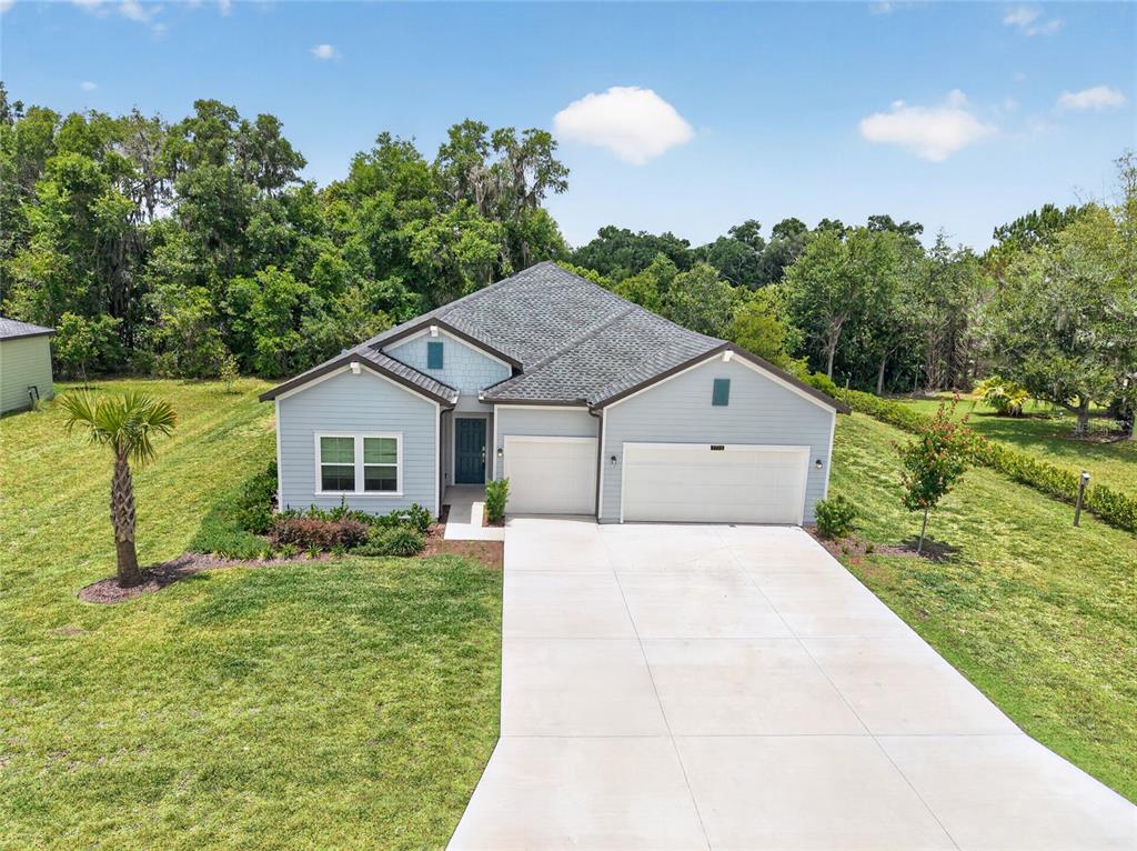 A light blue single-story house features a three-car garage and a concrete driveway — 7772 SW 195TH AVENUE, DUNNELLON, FL