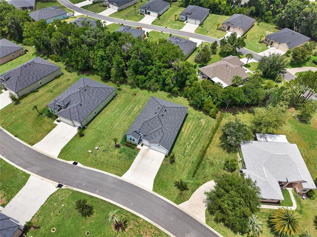 An aerial view shows several single-family homes with gray roofs surrounded by green lawns — 7772 SW 195TH AVENUE, DUNNELLON, FL