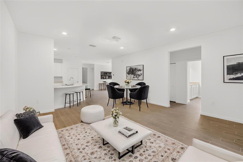 An open-concept living and dining area features white walls, light wood flooring, and modern furniture — 7772 SW 195TH AVENUE, DUNNELLON, FL