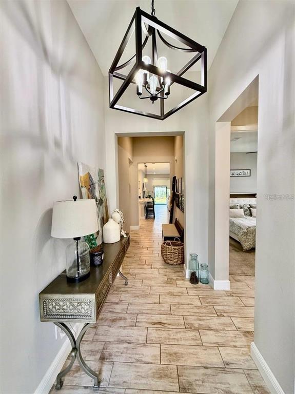 A hallway features light wood-look tile flooring, a geometric pendant light, and a console table — 4035 MAURICE AVENUE, ODESSA, FL