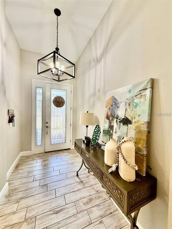 An entryway features a wood-look tile floor, a metal lantern chandelier, and a console table — 4035 MAURICE AVENUE, ODESSA, FL