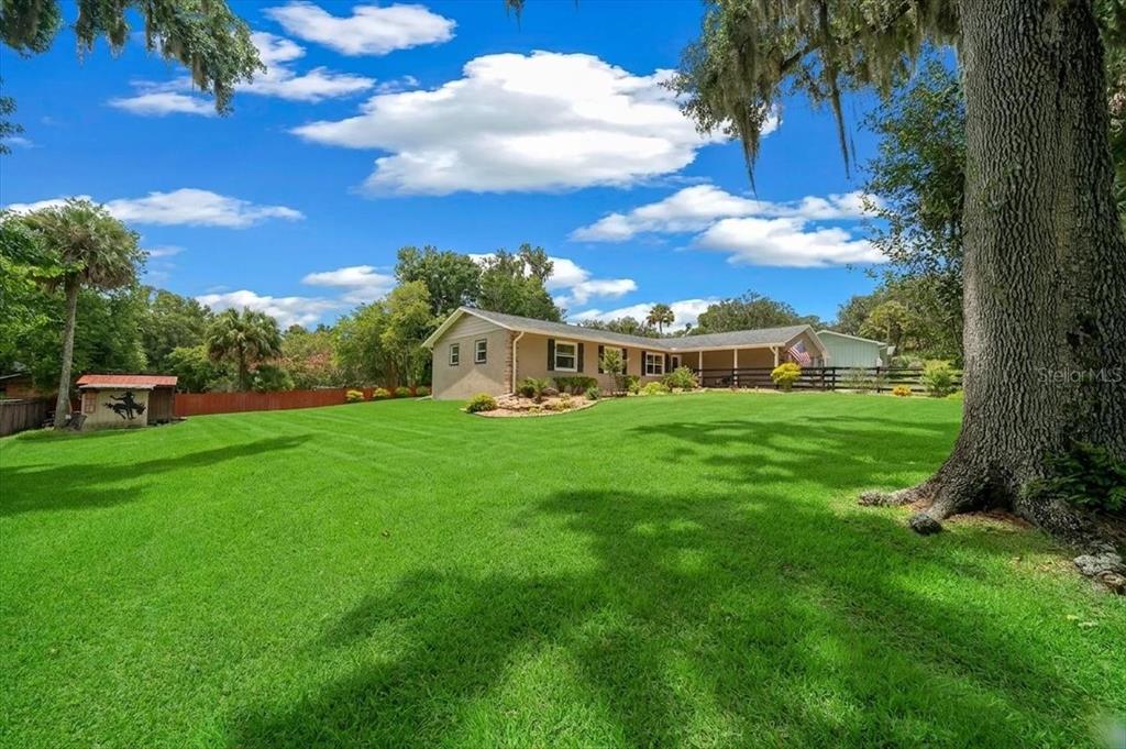 A single-story house with a large green lawn, mature trees, and a small shed — 530 SW 35TH STREET, OCALA, FL