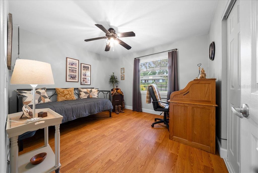 A bedroom with a daybed, wooden desk, ceiling fan, and hardwood floors — 530 SW 35TH STREET, OCALA, FL