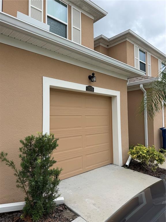A beige stucco house exterior features a single-car garage with a white frame — 11976 SKY ACRES TERRACE, BRADENTON, FL