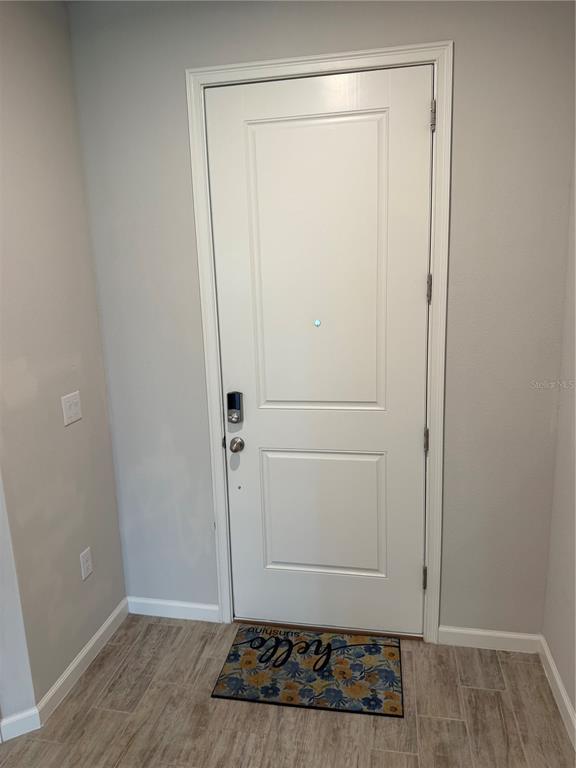 A white front door with a smart lock and a floral welcome mat — 11976 SKY ACRES TERRACE, BRADENTON, FL