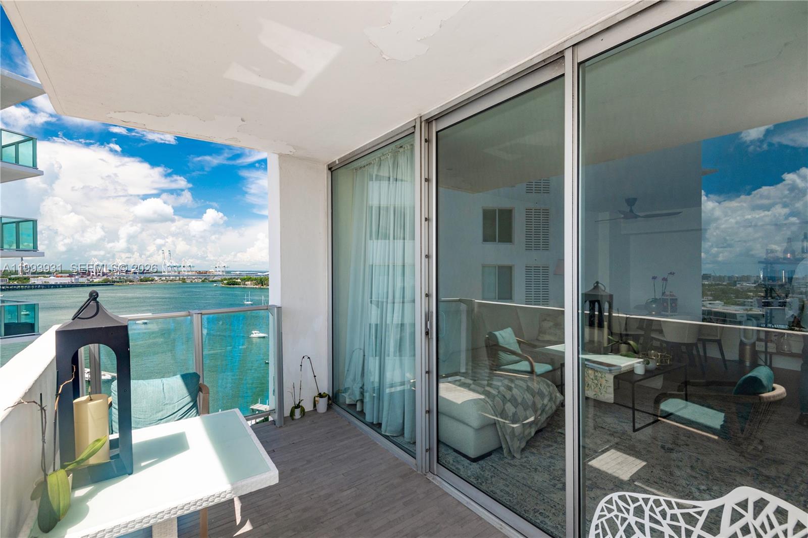 A balcony with a glass railing overlooks a bay with a view of the city — 1100 West Ave # 1427, Miami Beach FL 33139, MIAMI BEACH, FL