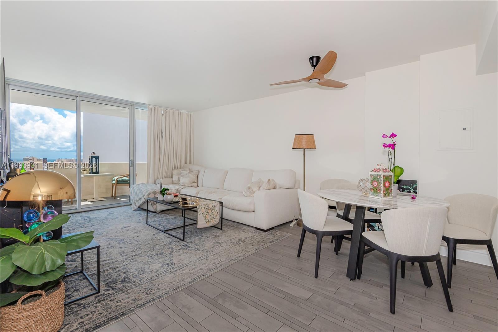 A living and dining area features a white sofa, marble table, and balcony access — 1100 West Ave # 1427, Miami Beach FL 33139, MIAMI BEACH, FL