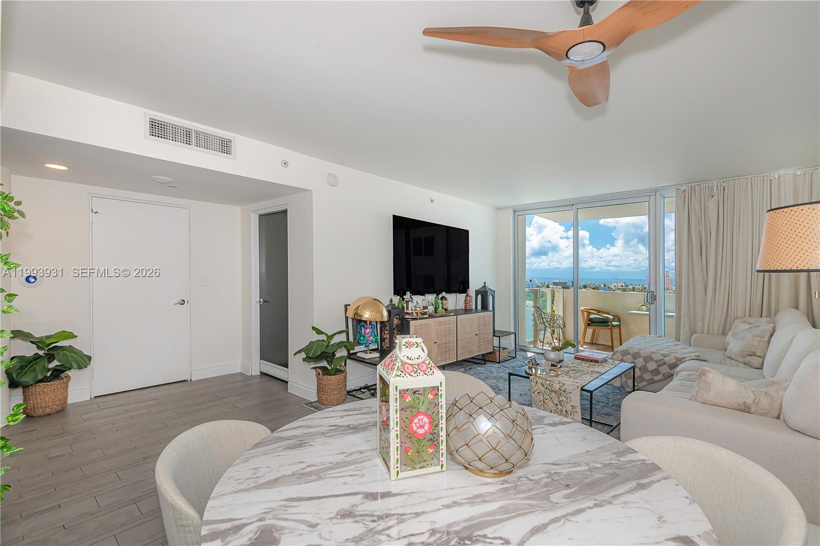 A living and dining area features a marble table, white sofa, and balcony with ocean views — 1100 West Ave # 1427, Miami Beach FL 33139, MIAMI BEACH, FL