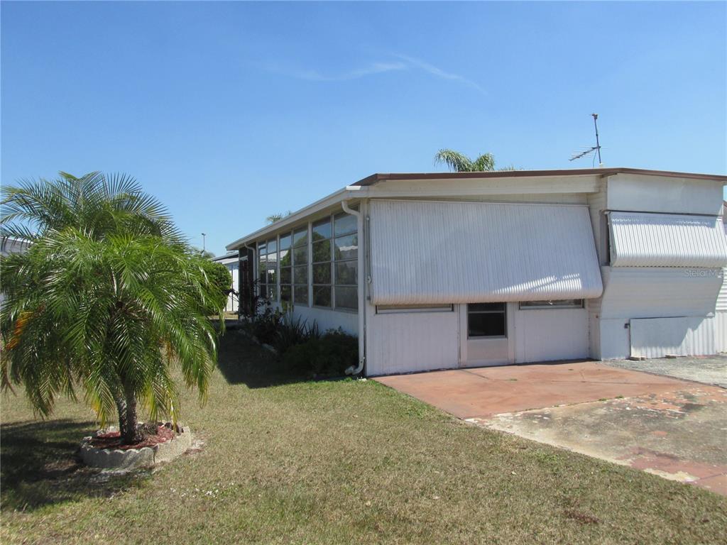 A white mobile home with a metal awning and a small palm tree in the yard — 10 RED QUILL CIRCLE, LAKE WALES, FL