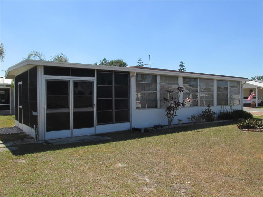 A single-story manufactured home with a screened-in porch and white siding under a clear sky — 10 RED QUILL CIRCLE, LAKE WALES, FL