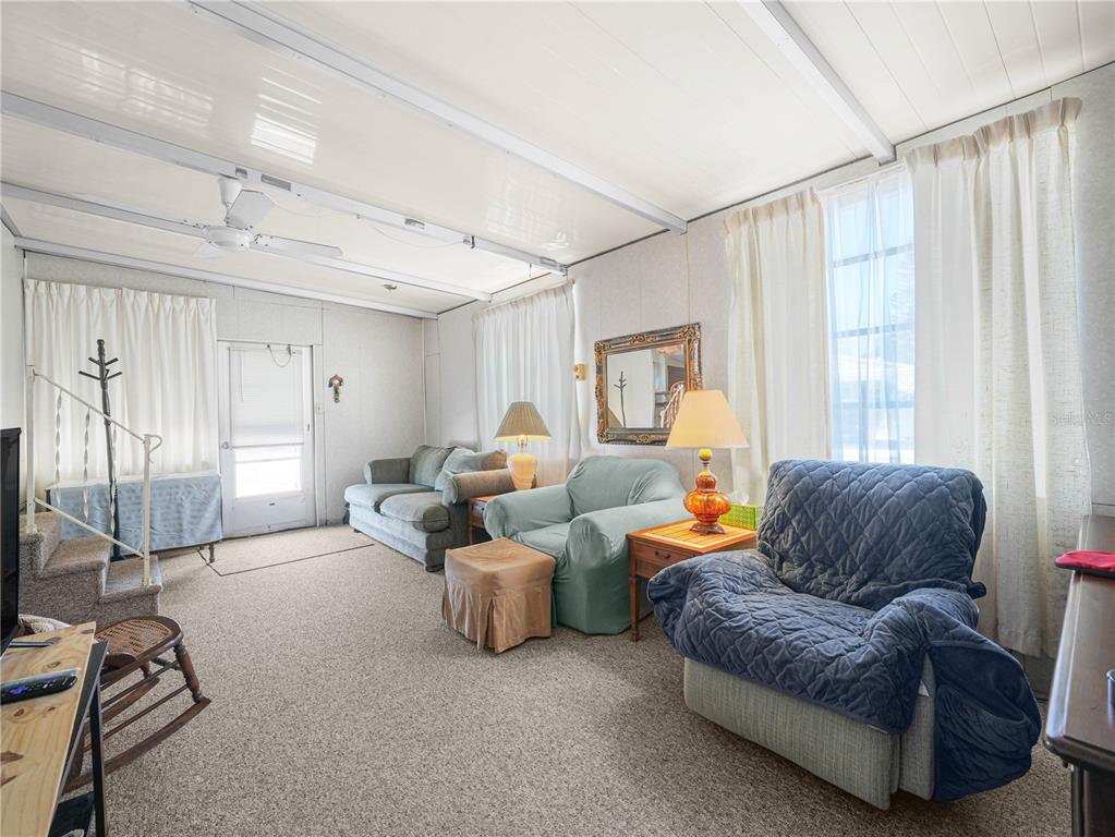A living room features carpeted floors, a ceiling fan, and several pieces of upholstered furniture — 10 RED QUILL CIRCLE, LAKE WALES, FL