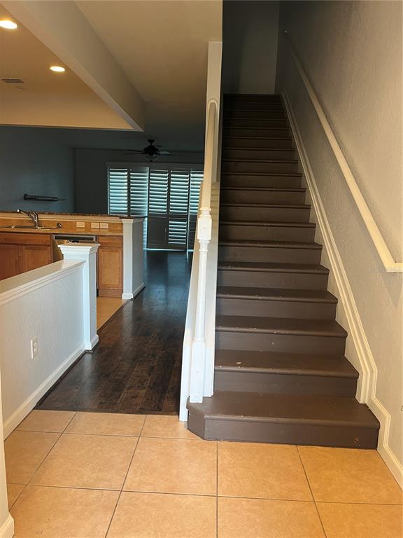A staircase with dark steps sits beside a kitchen area with wood cabinets and flooring — 4971 SW 45TH STREET UNIT na, OCALA, FL