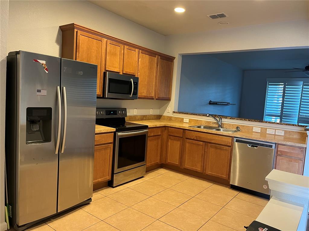 A kitchen features wood cabinets, stainless steel appliances, and tan tile flooring — 4971 SW 45TH STREET UNIT na, OCALA, FL