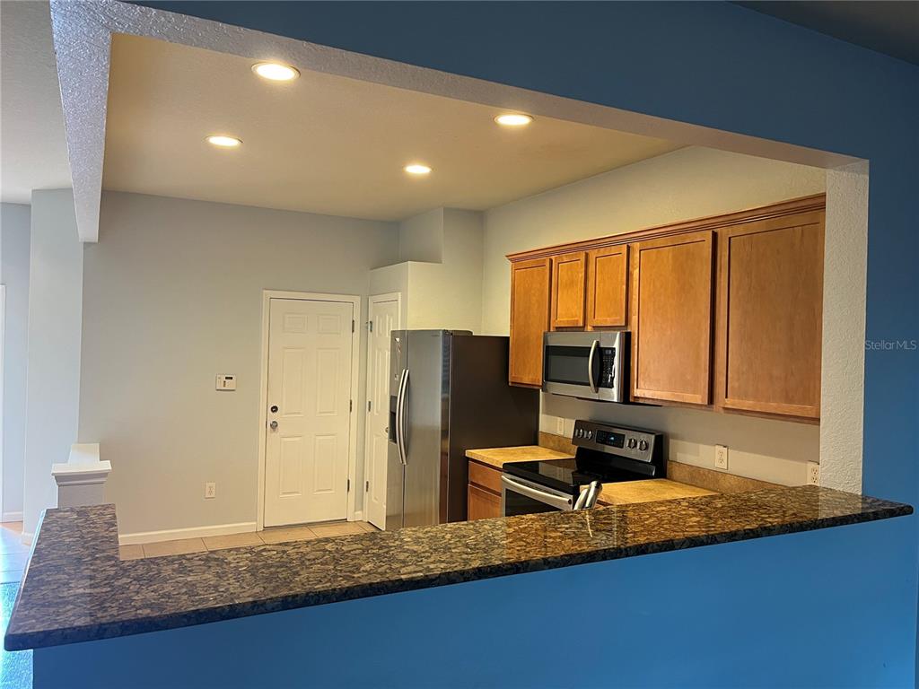 A kitchen features wood cabinets, stainless steel appliances, and a dark granite breakfast bar — 4971 SW 45TH STREET UNIT na, OCALA, FL