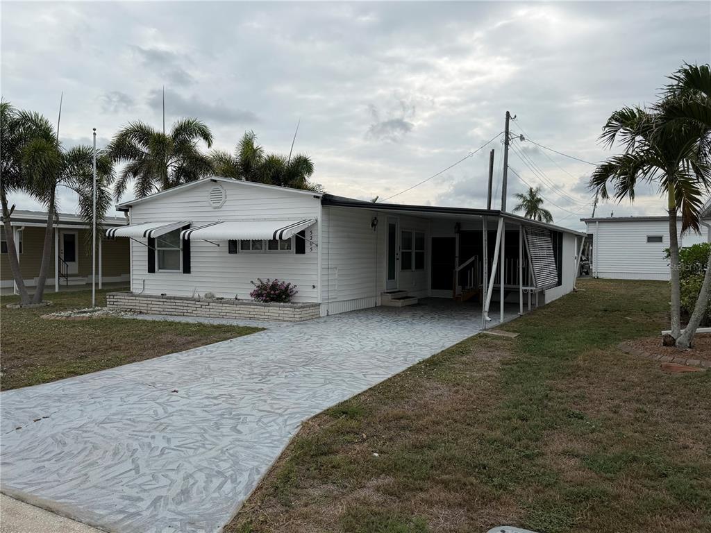 A white mobile home with a patterned concrete driveway and a covered carport — 5205 5TH STREET E, BRADENTON, FL
