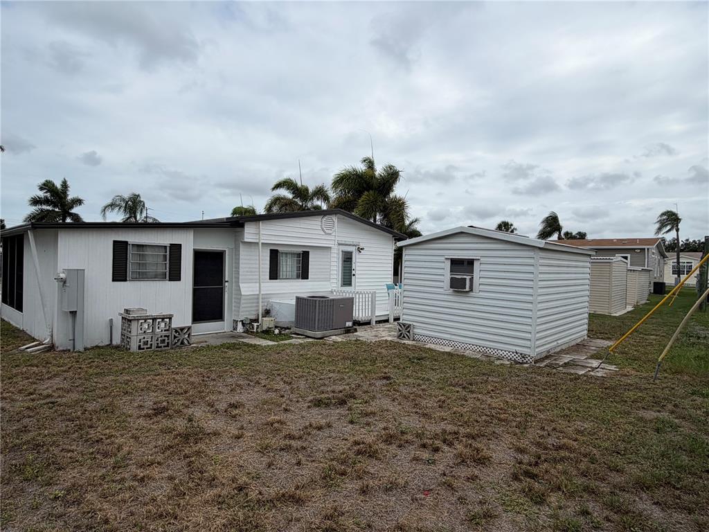 The exterior of a white mobile home features a detached shed and a grassy yard — 5205 5TH STREET E, BRADENTON, FL