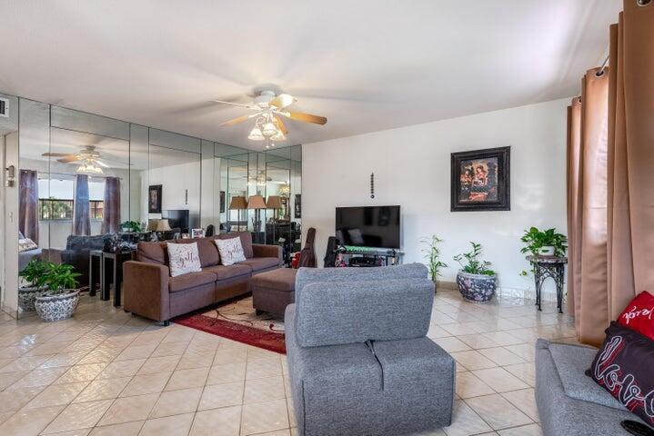 A living room features tiled floors, a mirrored wall, a brown sofa, and gray chairs — 657 Brittany N, Delray Beach FL 33446, DELRAY BEACH, FL