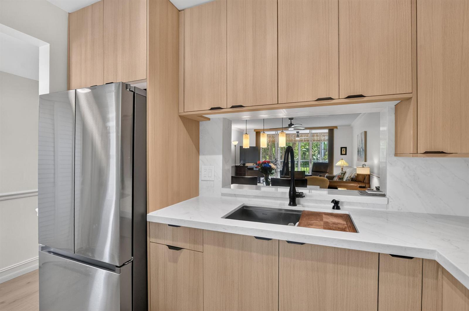 A kitchen features light wood cabinets, a stainless steel refrigerator, and a white marble countertop — 2809 Florida Boulevard # 208, Delray Beach FL 33483, DELRAY BEACH, FL