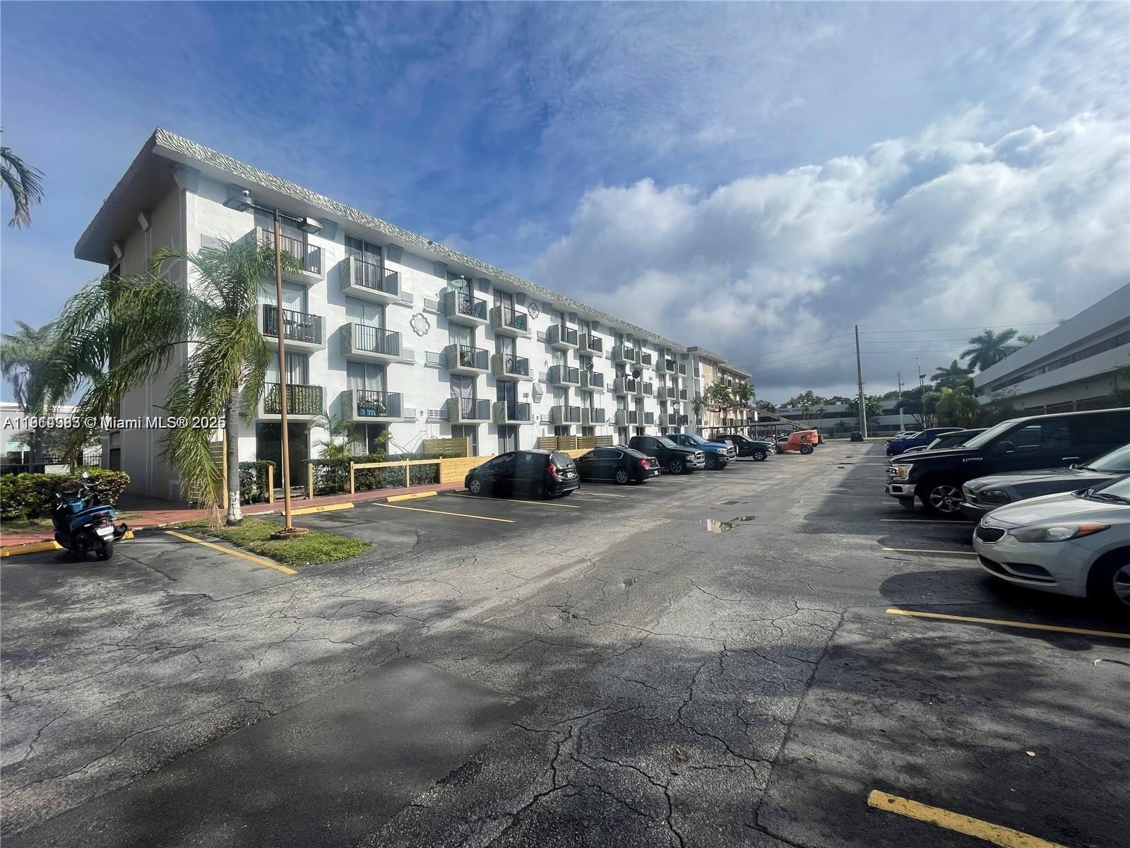A multi-story apartment building stands beside a parking lot filled with various parked cars — 16450 NW 2nd Ave # 109, Miami FL 33169, MIAMI, FL