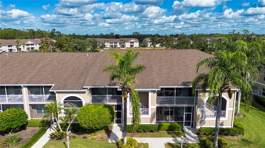 An aerial view of a multi-story apartment building with screened balconies and palm trees — 5300 HYLAND HILLS AVENUE UNIT U2016, SARASOTA, FL